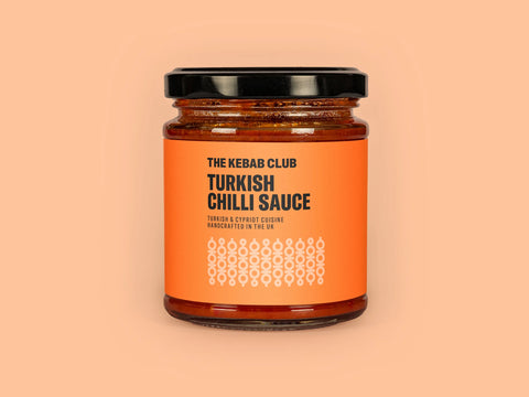 A jar of The Kebab Club Turkish Chilli Sauce with a label that includes the product name and a brief description.