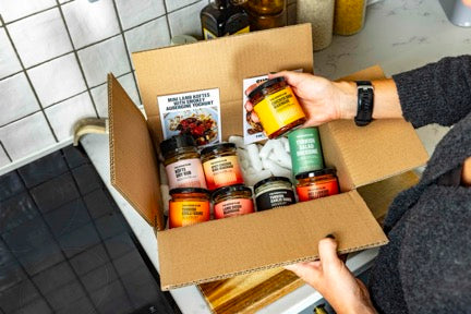 Person opening a box of food products on a kitchen counter.