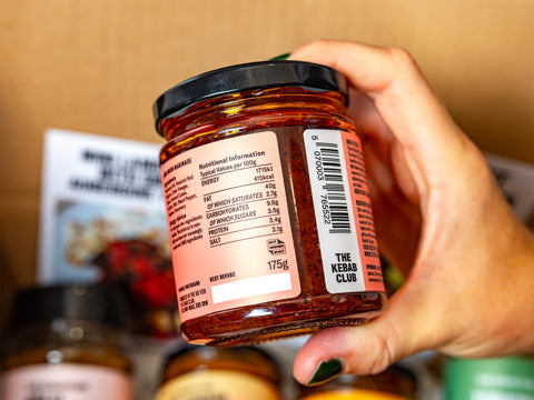 Hand holding a jar of The Kebab Club product with a blurred background
