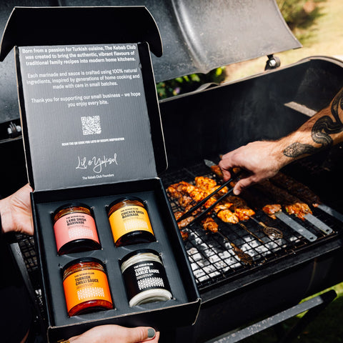 Person grilling food with a box of barbecue sauces in the foreground