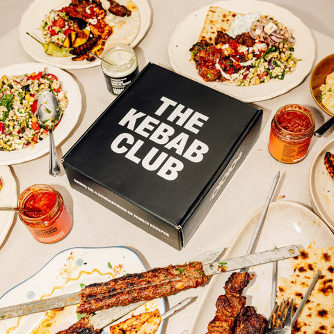Plates of food and 'The Kebab Club' box on a table.